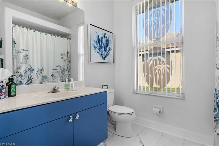 Full bath with marble finish floor, toilet, vanity, and baseboards