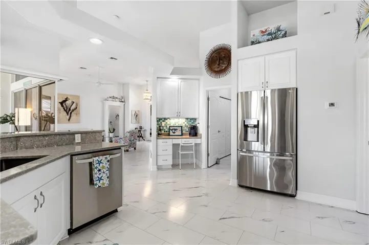 Kitchen with marble finish floor, stainless steel appliances, a ceiling fan, tasteful backsplash, and white cabinetry