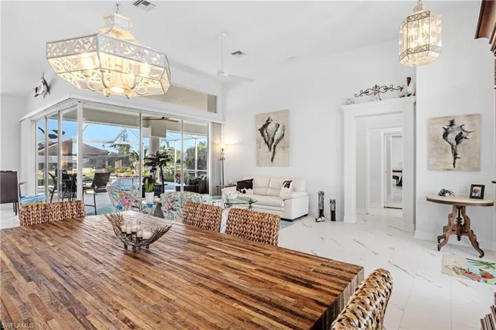Dining space featuring marble finish floor, ceiling fan with notable chandelier, baseboards, and visible vents