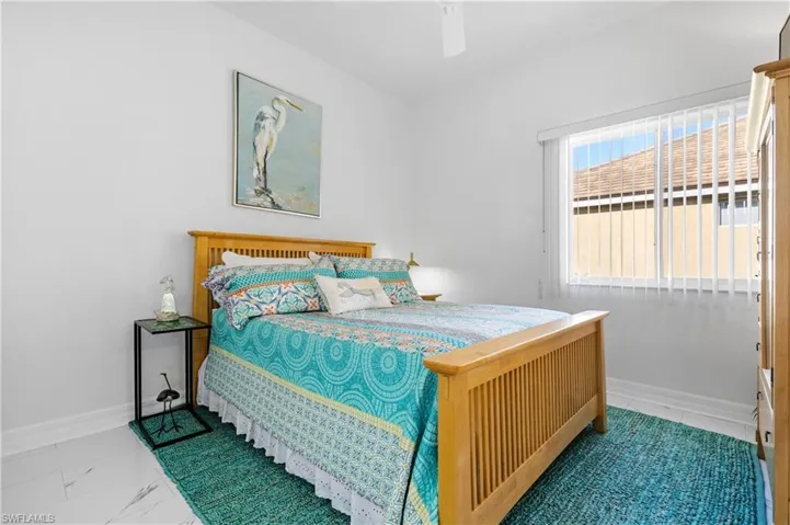 Bedroom featuring baseboards, marble finish floor, and a ceiling fan