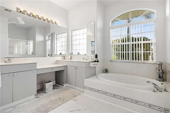 Bathroom with a bath, marble finish floor, a wealth of natural light, and visible vents