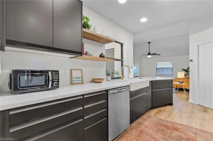 Kitchen with open shelves, light wood-style floors, dishwasher, black microwave, and ceiling fan