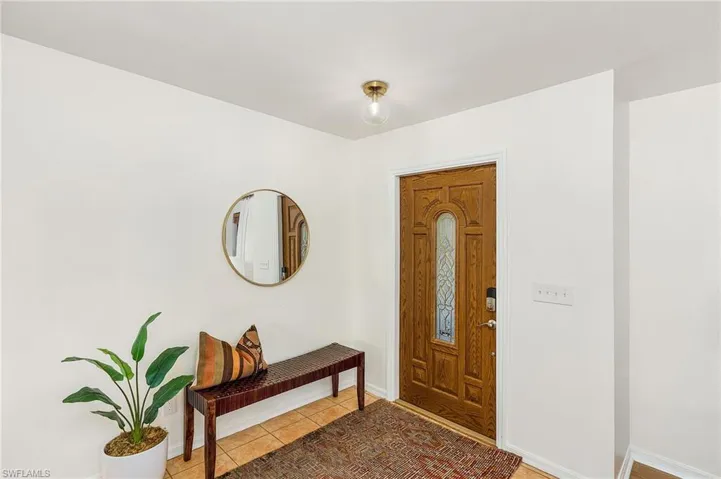 Foyer with light tile patterned floors and baseboards