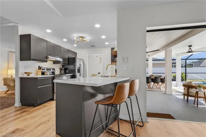 Kitchen with a kitchen breakfast bar, stainless steel appliances, light wood-type flooring, recessed lighting, and under cabinet range hood