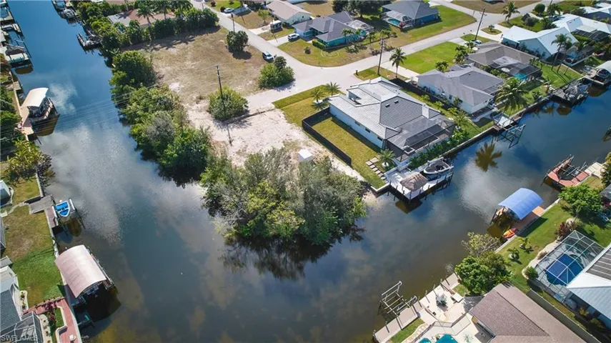 Waterfront property featuring canal access, mature trees, and a developed surrounding neighborhood