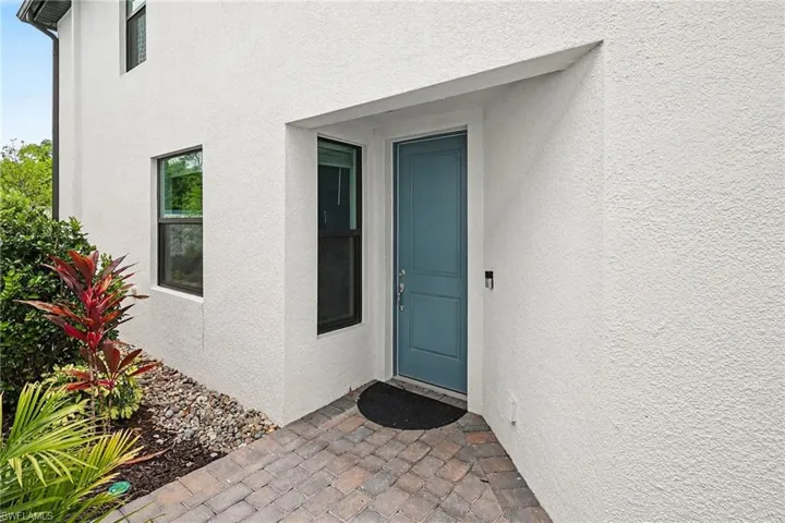 Inviting entryway featuring a blue panel door, stucco exterior, and black-framed windows
