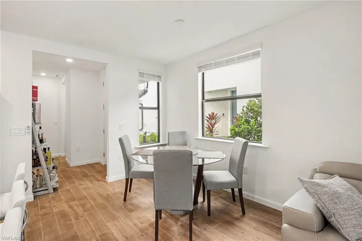 Dining area featuring wood-finish flooring, two large windows, recessed ceiling lighting, and a white baseboard trim