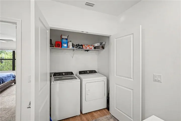 Laundry closet featuring a top-load washer and front-load dryer, wire shelving, and wood-finish flooring