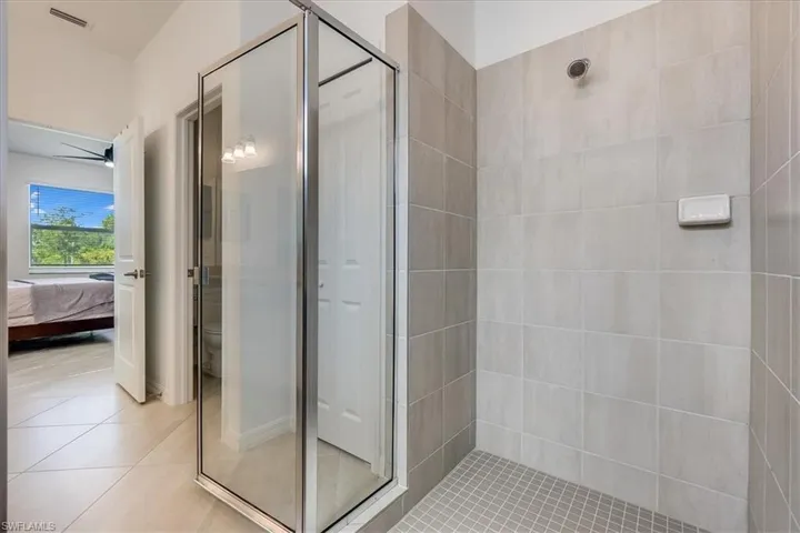 Primary bathroom with toilet, tile floors, and a shower with door