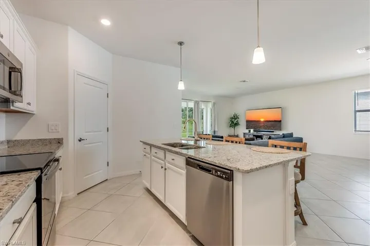 Kitchen with sink, white cabinets, a kitchen island with sink, and appliances with stainless steel finishes.