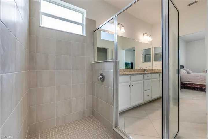 Primary bathroom featuring tile floors, a shower with door, and vanity