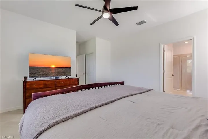 Bright and airy primary bedroom with connected bathroom and ceiling fan.