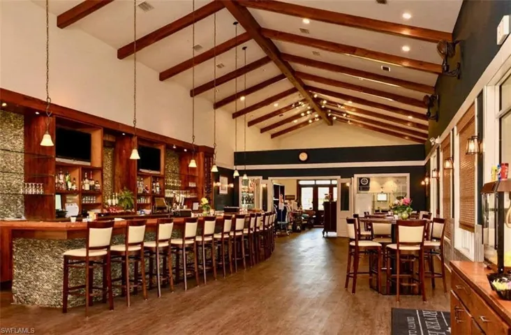 Restaurant/lounge featuring high vaulted ceiling, dark wood-type flooring, hanging light fixtures, and beam ceiling
