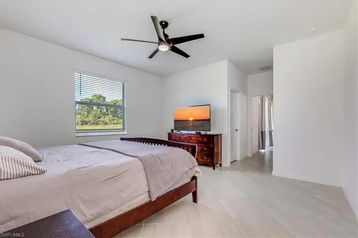 Tiled primary bedroom with ceiling fan