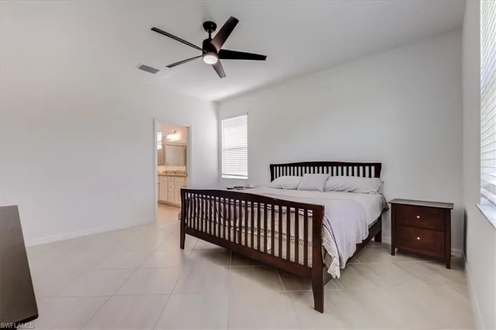 Tiled primary bedroom featuring ceiling fan and ensuite primary bath.