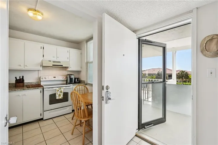 Kitchen featuring electric stove, white cabinets, light tile patterned floors, tasteful backsplash, and a textured ceiling