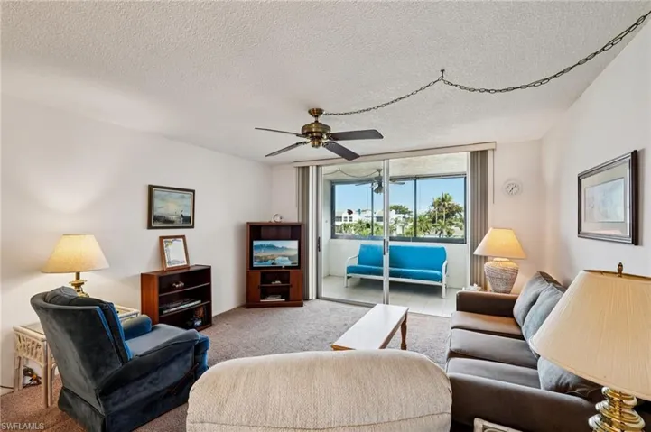 Carpeted living area with a ceiling fan and a textured ceiling