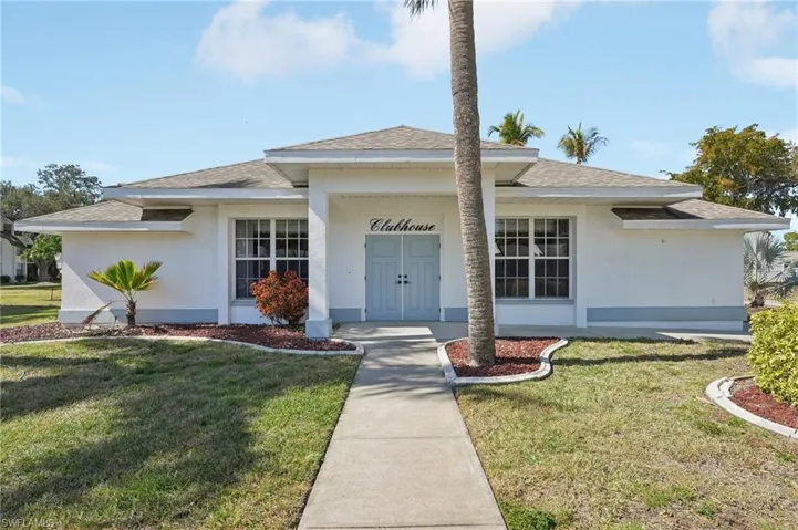 View of front of property with a shingled roof, a front lawn, and stucco siding