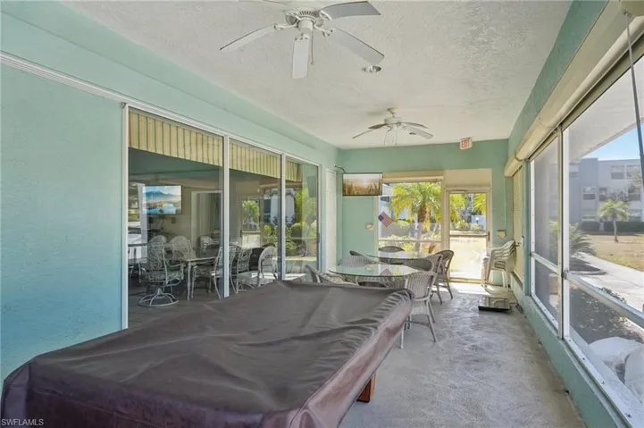 Sunroom with a ceiling fan, outdoor dining area, billiards table, a textured ceiling, and carpet