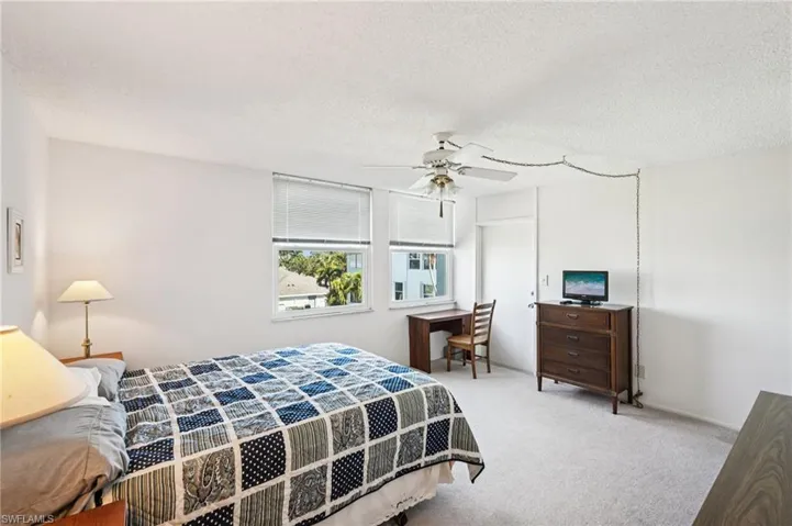 Carpeted bedroom featuring a textured ceiling, a ceiling fan, and a desk