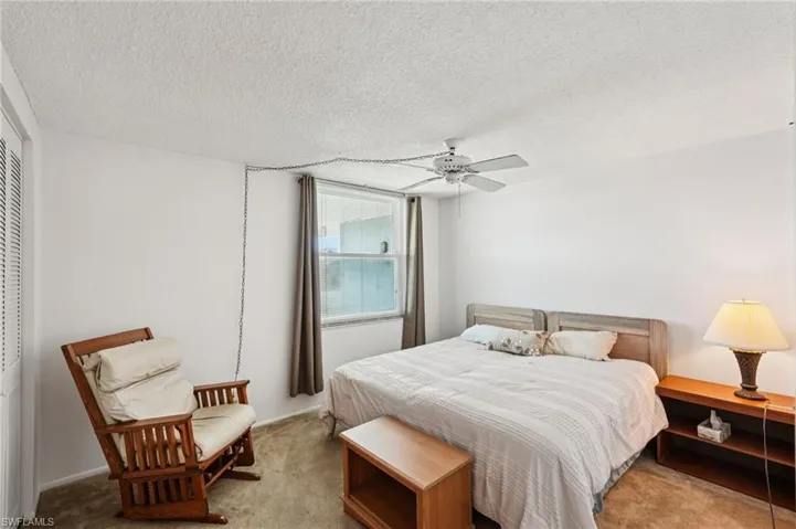 Carpeted bedroom with ceiling fan and a textured ceiling
