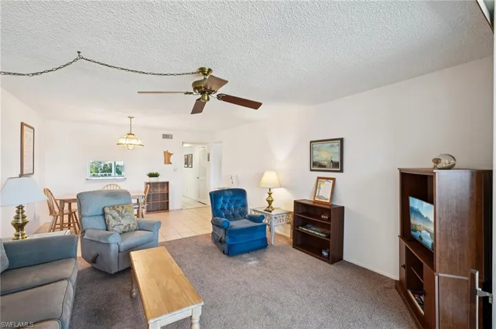 Carpeted living area featuring ceiling fan and a textured ceiling