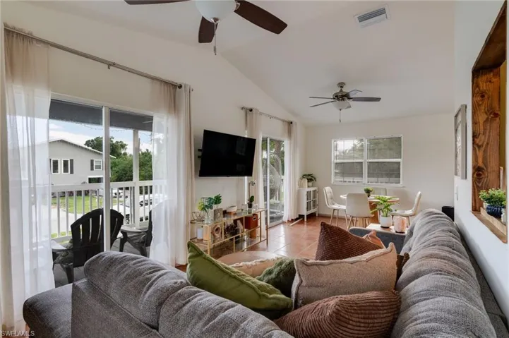 Spacious living area featuring a vaulted ceiling, ceiling fans, and tiled flooring