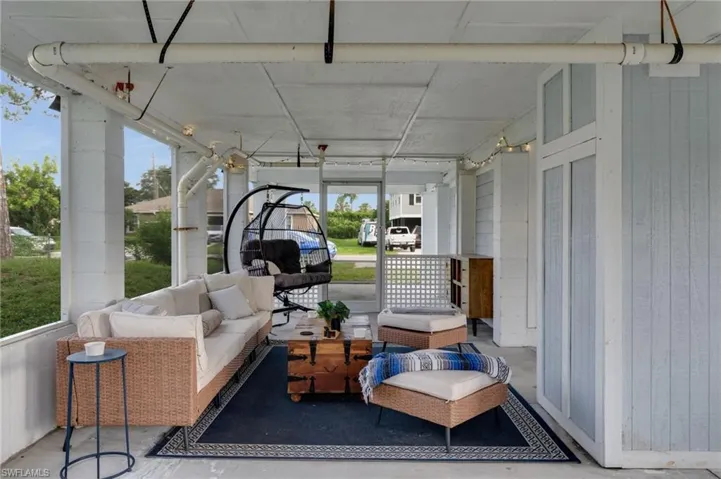 Covered porch featuring light blue siding, white trim, and a concrete floor