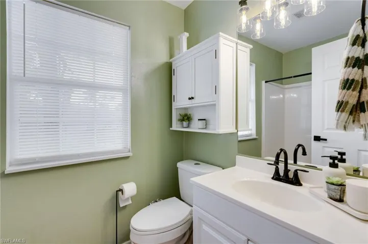 Bathroom featuring a white vanity with an integrated sink, matte black faucet, and a large wall mirror