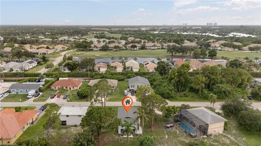 Aerial perspective showcasing residential properties with a golf course and water feature visible in the background