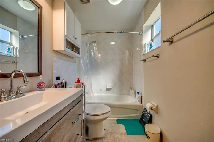 Full bathroom with tiled shower / bath combo, toilet, and vanity