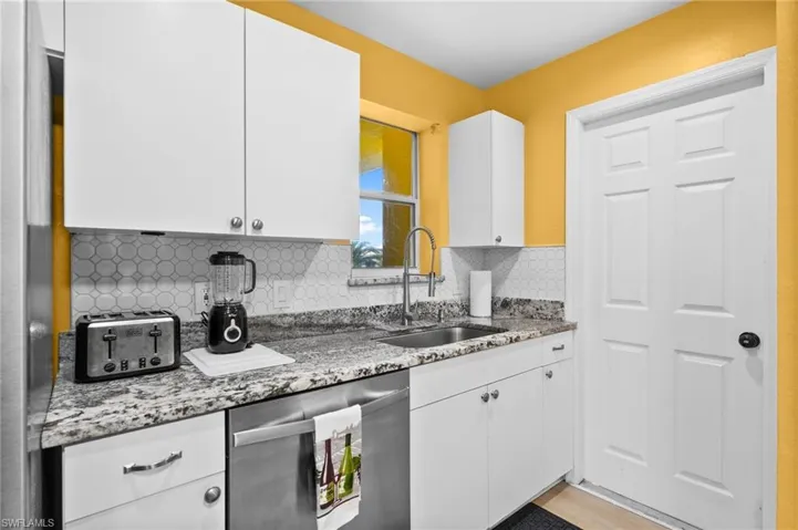 Kitchen with sink, white cabinets, and stainless steel dishwasher