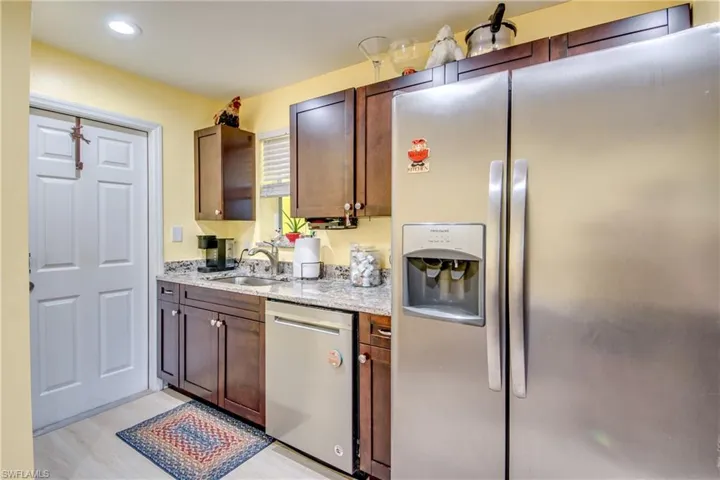 Kitchen featuring stainless steel appliances, light stone counters, light hardwood / wood-style floors, and sink