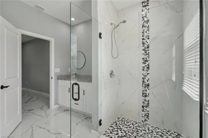 Bathroom with tile patterned floors, a shower with door, and plenty of natural light