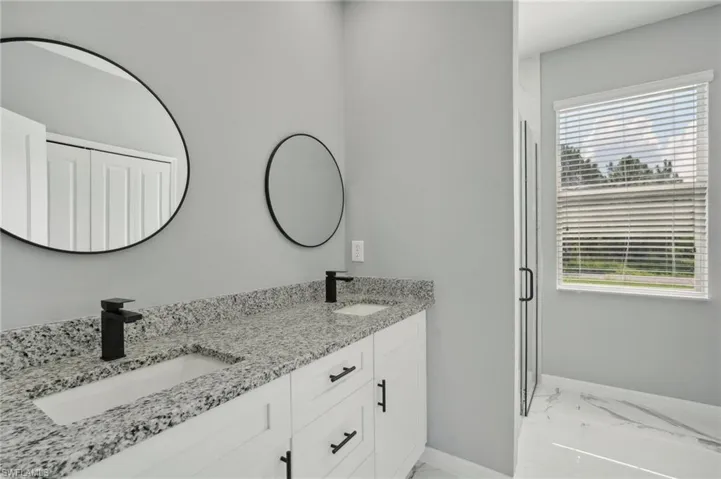Bathroom with a bathtub, dual vanity, and a wealth of natural light