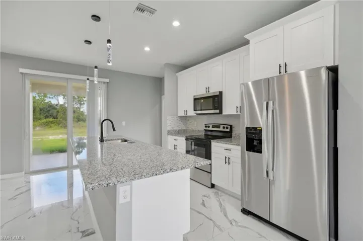 Kitchen with stainless steel appliances, hanging light fixtures, light tile patterned floors, tasteful backsplash, and sink