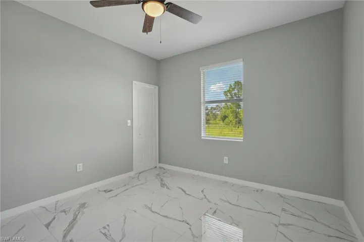 Empty room featuring ceiling fan and tile patterned floors