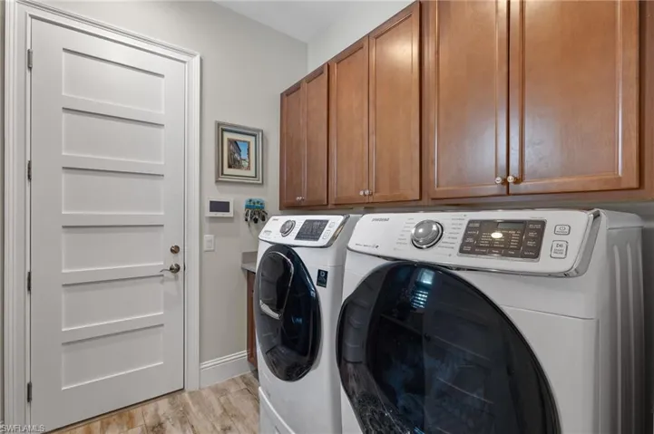 Laundry area with cabinets, light wood-type flooring, and independent washer and dryer