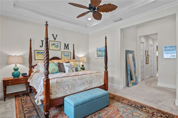Carpeted bedroom with ceiling fan and a tray ceiling