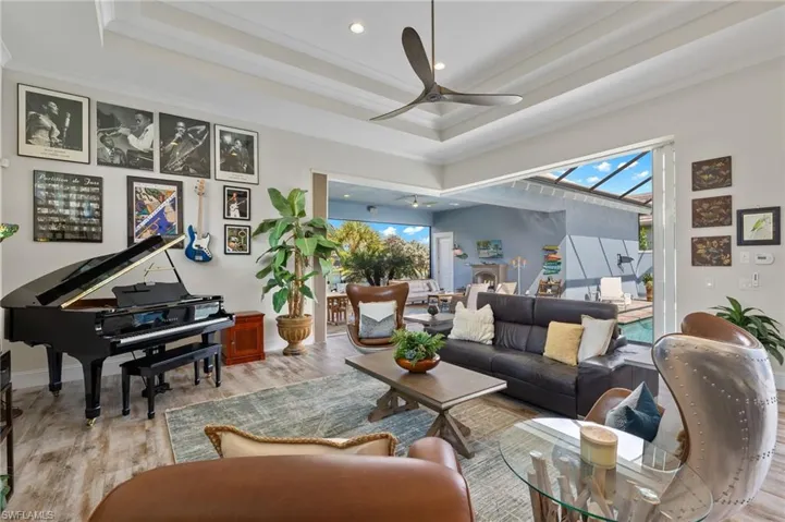 Living room featuring ceiling fan, crown molding, light hardwood / wood-style flooring, and a tray ceiling