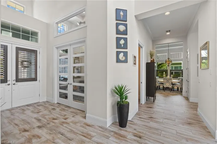 Entryway featuring french doors, light hardwood / wood-style floors, ornamental molding, and a high ceiling