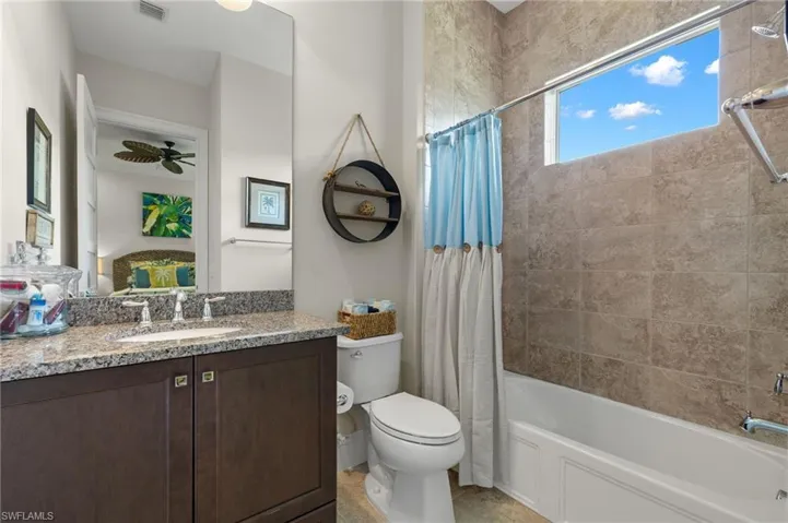 Full bathroom with ceiling fan, toilet, vanity, tile patterned flooring, and shower / bathtub combination with curtain