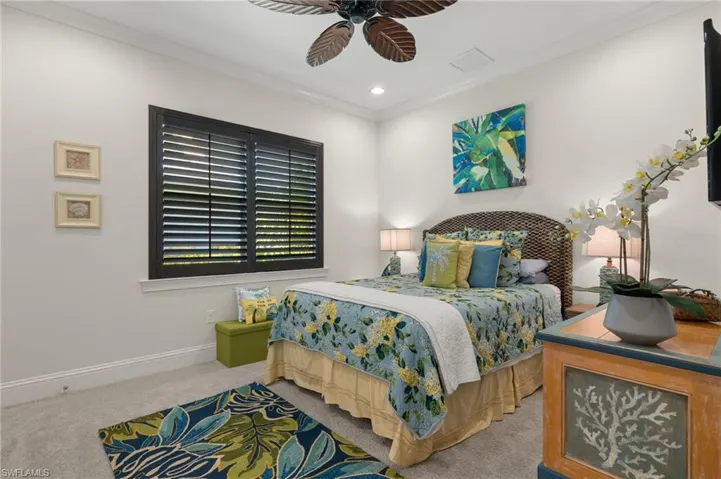 Bedroom with ceiling fan, crown molding, and light colored carpet