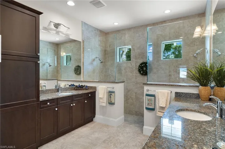 Bathroom with dual vanity, tile patterned floors, and a shower with shower door