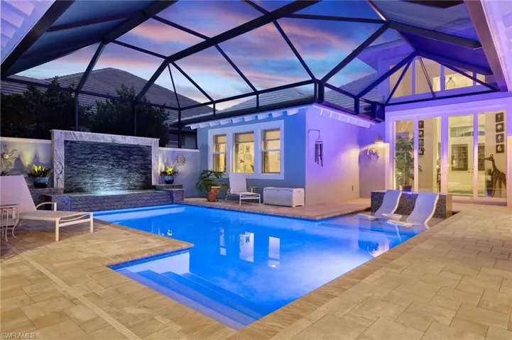 Pool at dusk featuring a lanai and a patio