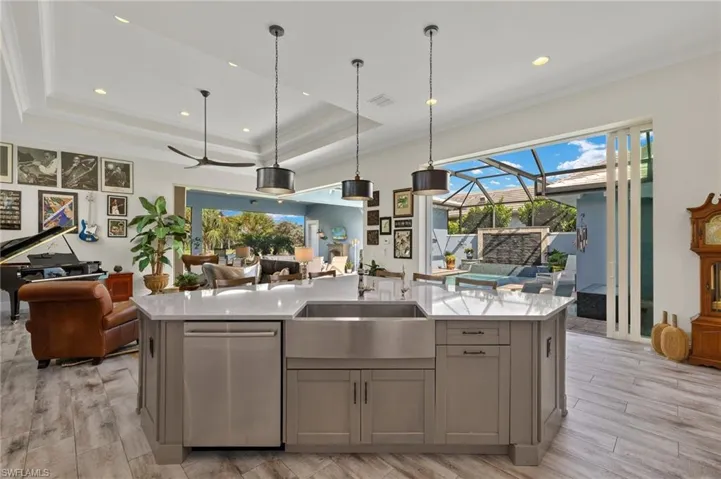 Kitchen with dishwasher, an island with sink, gray cabinets, sink, and a tray ceiling