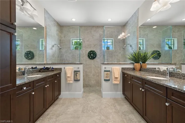 Bathroom with tile patterned floors, tile walls, vanity, and tiled shower