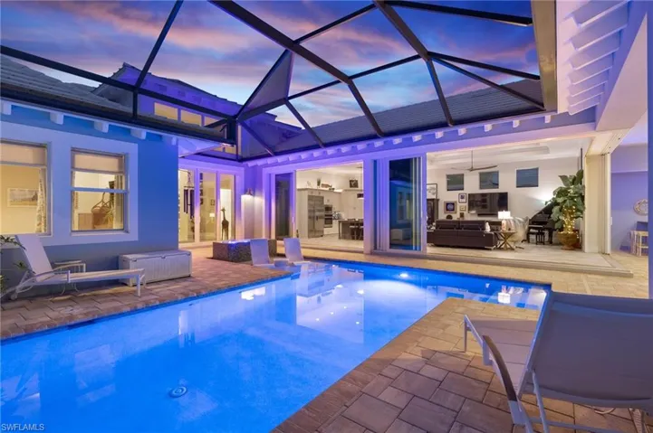 Pool at dusk featuring glass enclosure and a patio area