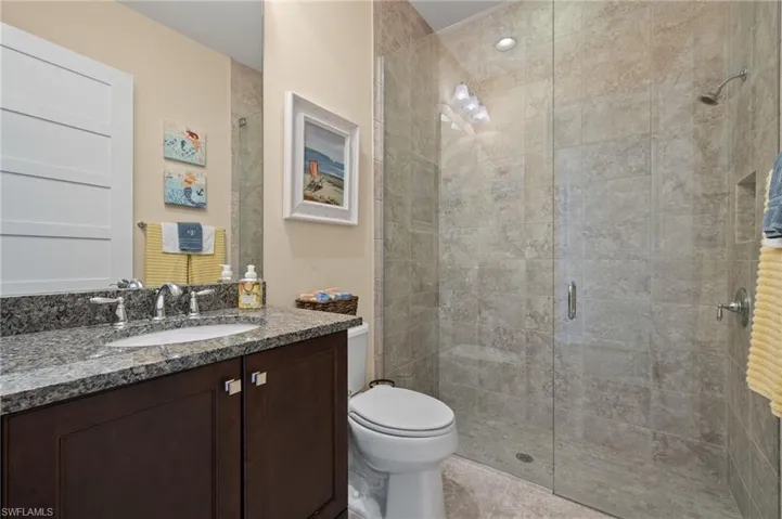 Bathroom featuring vanity, toilet, walk in shower, and tile patterned flooring