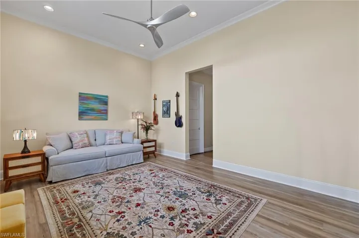 Living room featuring ceiling fan, ornamental molding, and hardwood / wood-style flooring